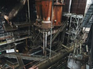 Industrial hopper discharging bulk material while a mounted vibrator operates beside the outlet.
