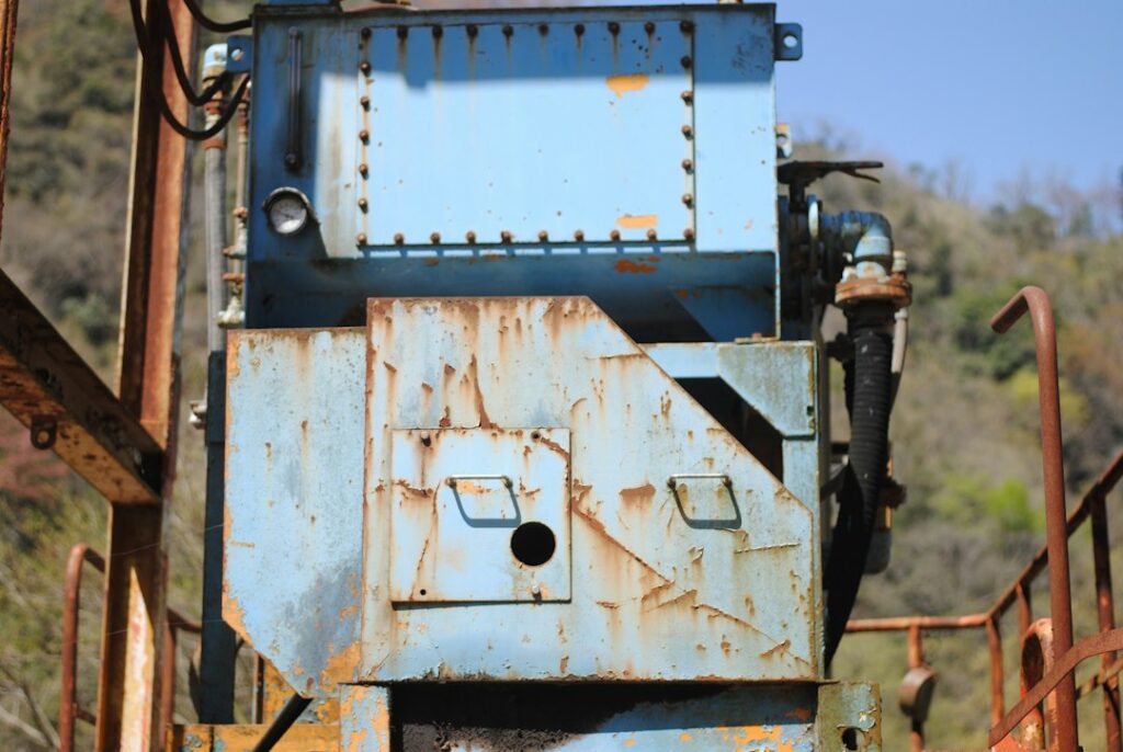 Worker inspecting an electric vibrator mounted on a steel hopper inside an industrial processing facility.